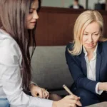 Boss gives employee feedback while pointing at a laptop screen