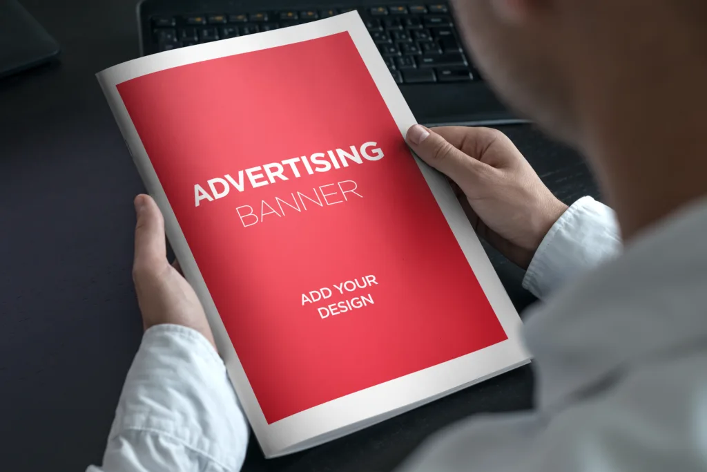 Hands hold a booklet that says "Advertising banner add your design."