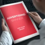 Man in white, long-sleeved shirt holds a book with a red cover and white margins that says "advertising banner."
