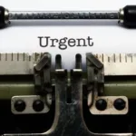 Old-fashioned typewriter with a paper in it that says the word "Urgent"