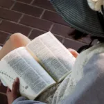 a girl wearing a hat is reading a book