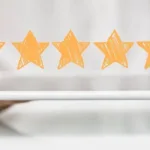 Five yellow stars hanging above a white tablet held by a had