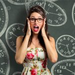 Woman in front of chalkboard with clocks holds her hands to her faces with her mouth open. Getting faster as a copywriter may happen naturally, but it shouldn't be your goal.