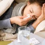 Sick woman in bed with tissue holding her head