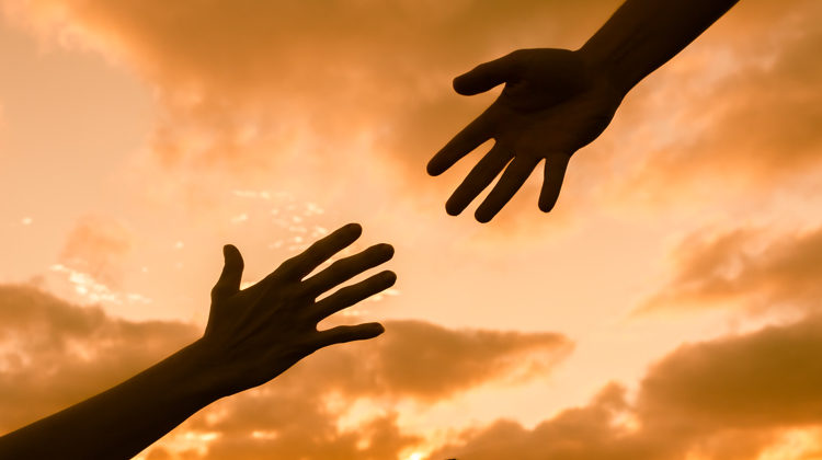 Two silhouette hands against an orange sky reach toward each other ... here's how to reach out to influencers the right way.