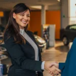 Woman in blazer smiling while shaking a man's hand