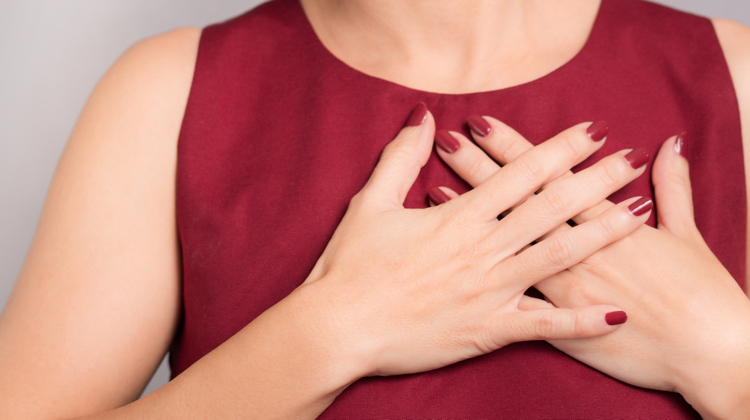 Person with maroon tank top and matching nails holds her hands crossed over her heart.