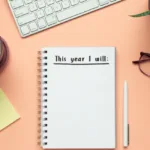 A notebook on a desk that reads "this year I will."