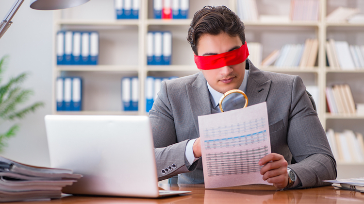 A man sitting blindfolded at a desk.