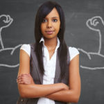 Woman in front of a chalkboard that has strong arms drawn on it.