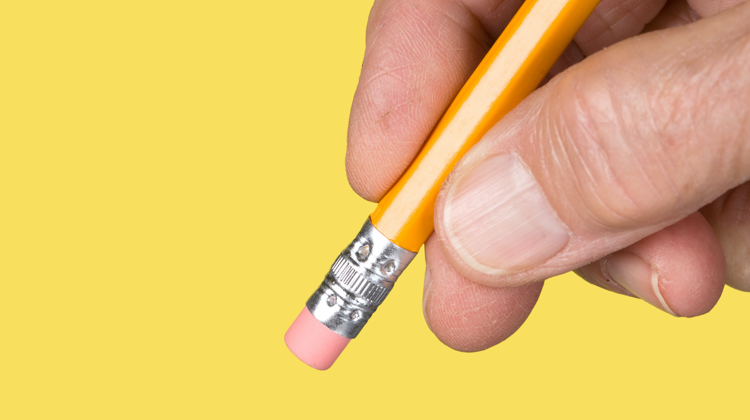 A hand holds a pencil with the eraser side down against a school-bus yellow background.