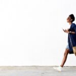 Woman walking in front of a white wall.