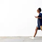 Woman walking in front of a white wall.