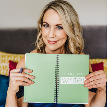 Founder Nicki Krawczyk holds up a green notebook that says Filthy Rich Writer.