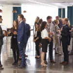 Group of people in business attire stand around in small groups to network