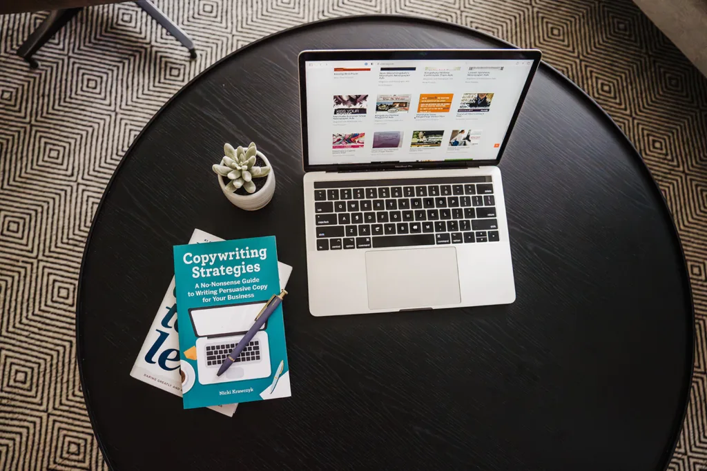 Laptop with copywriting portfolio site on the screen and copy of "Copywriting Strategies" book next to it, plus a succulent.