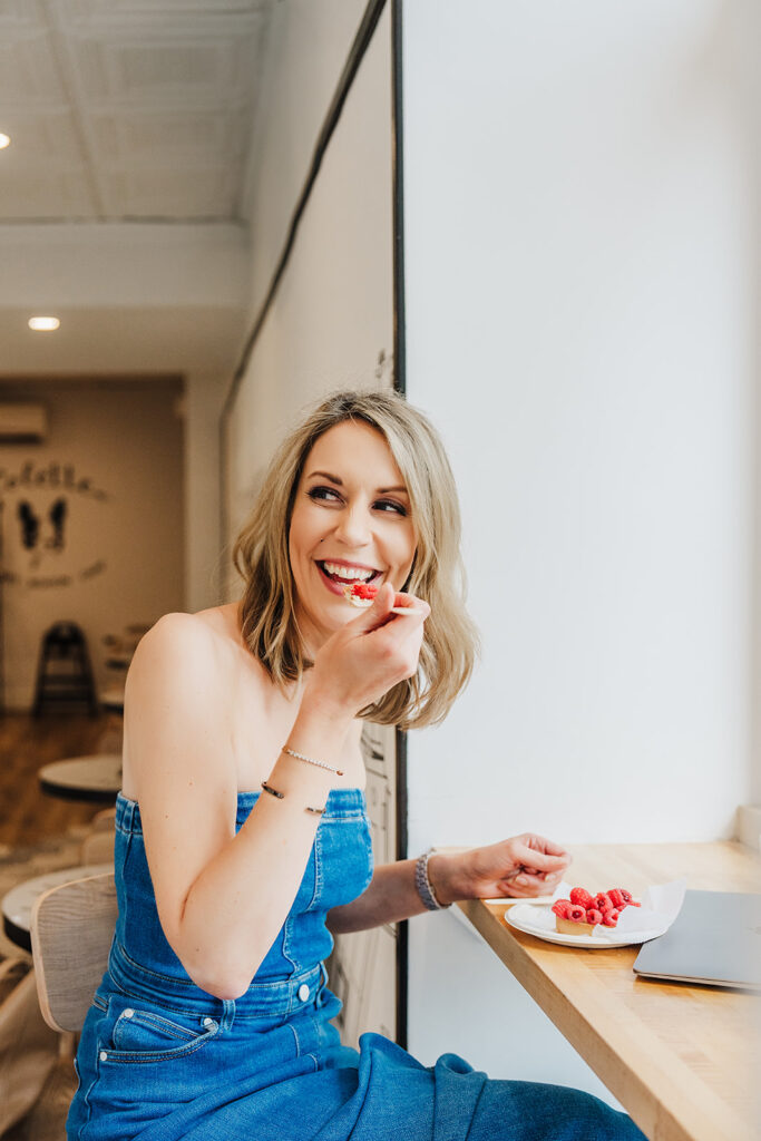 Nicki Krawczyk, founder of the Comprehensive Copywriting Academy and Filthy Rich Writer, bites into a pastry.